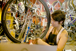 Sara Morris, who runs Mello Velo Bicycle Shop on Wescott Street with her husband, straightens the spokes on a tire on Tuesday afternoon. 