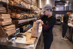 A Water Street Bagel Co. staff member packs food for morning pickup orders. Water Street Bagel Co., opened in 2018, is ranked the fifth best bagel shop in New York state by Yelp.