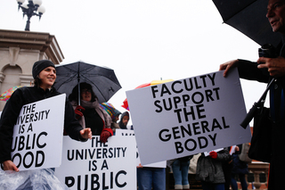 Joanna Spitzner, a VPA associate professor, passes out posterboard signs in support of THE General Body.